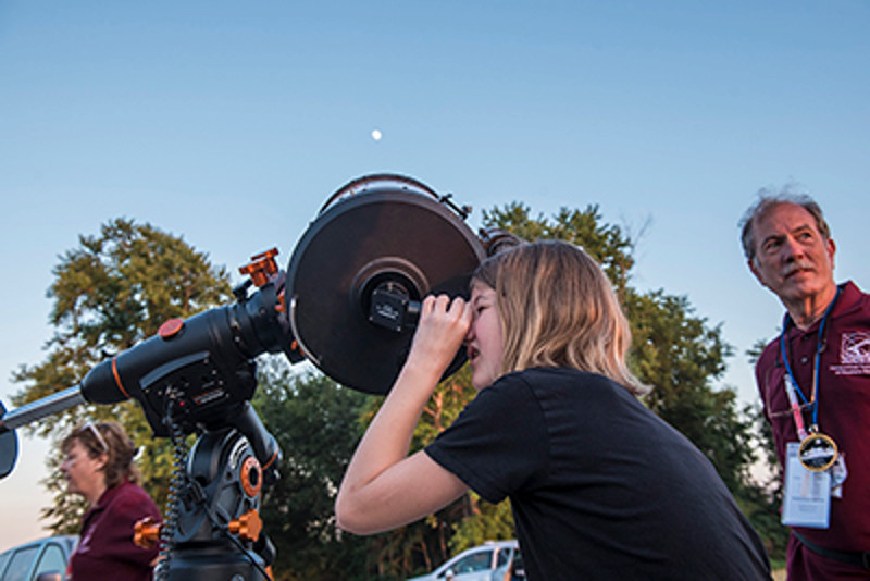 Student looks through a telescope at a public astronomy observation